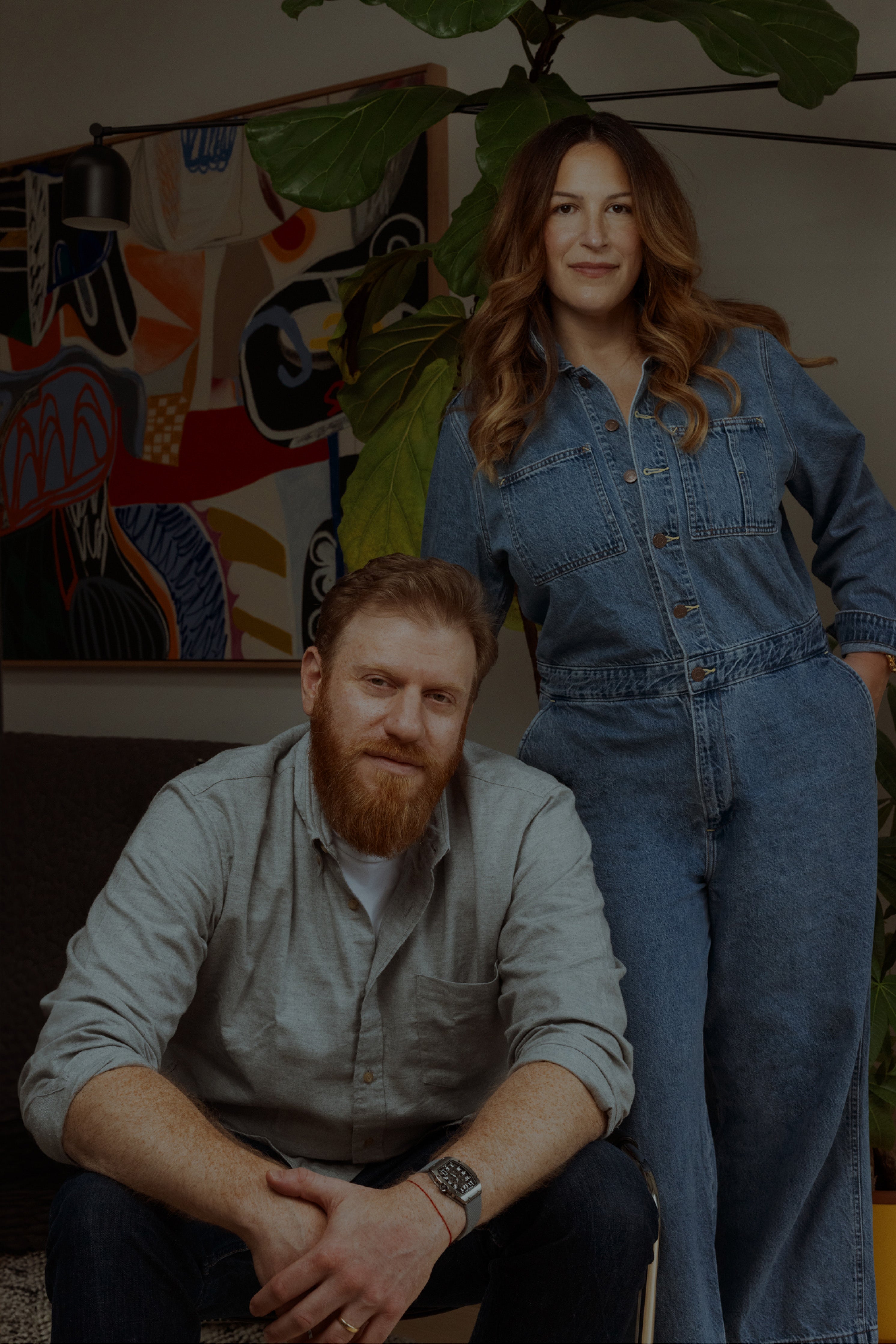 The founders Amy and Aaron with an abstract painting in the background.