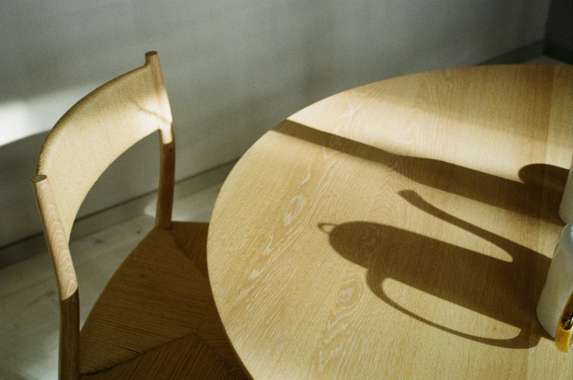 A shadow on a wooden table with chairs.