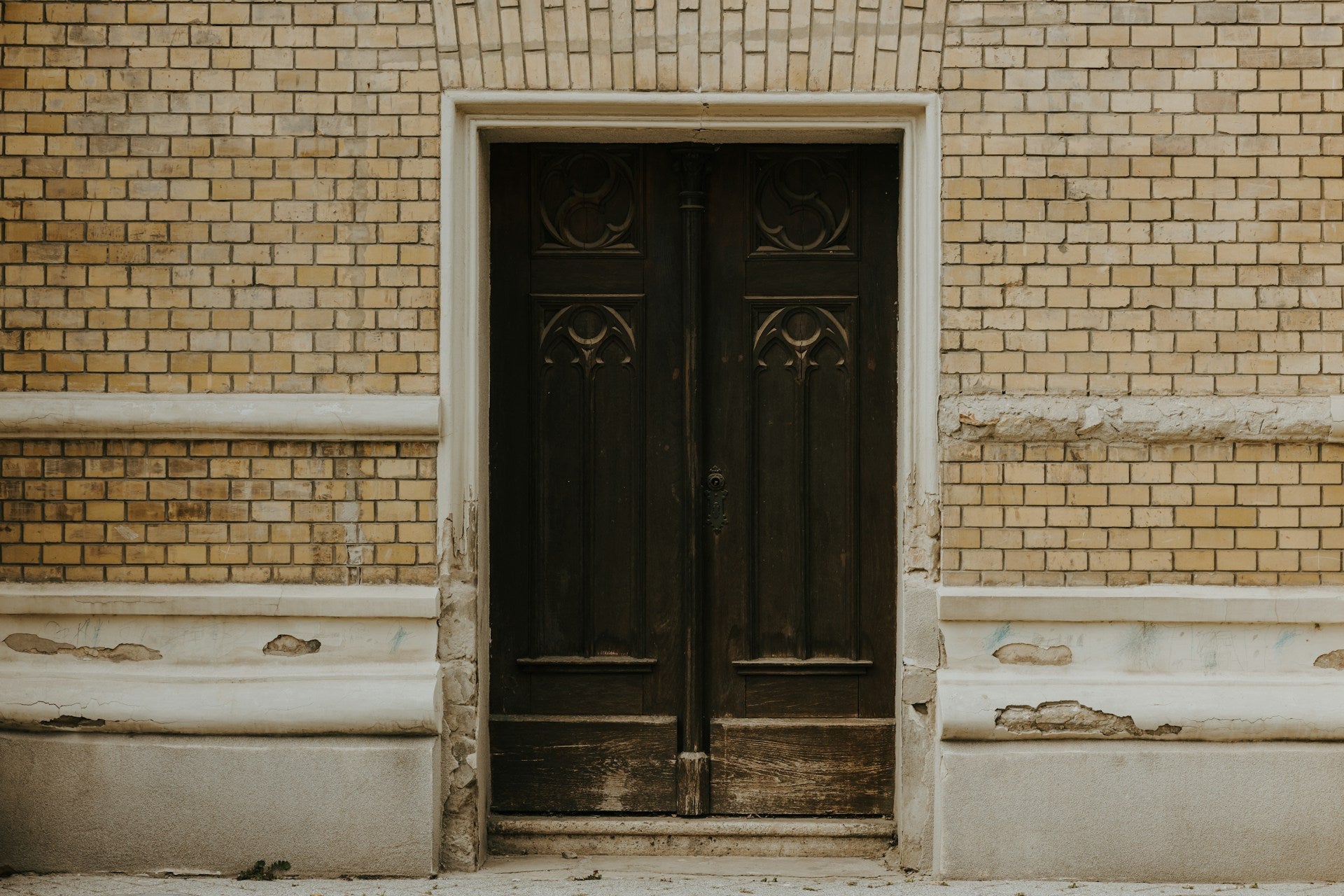 A brown brick building with two black doors.