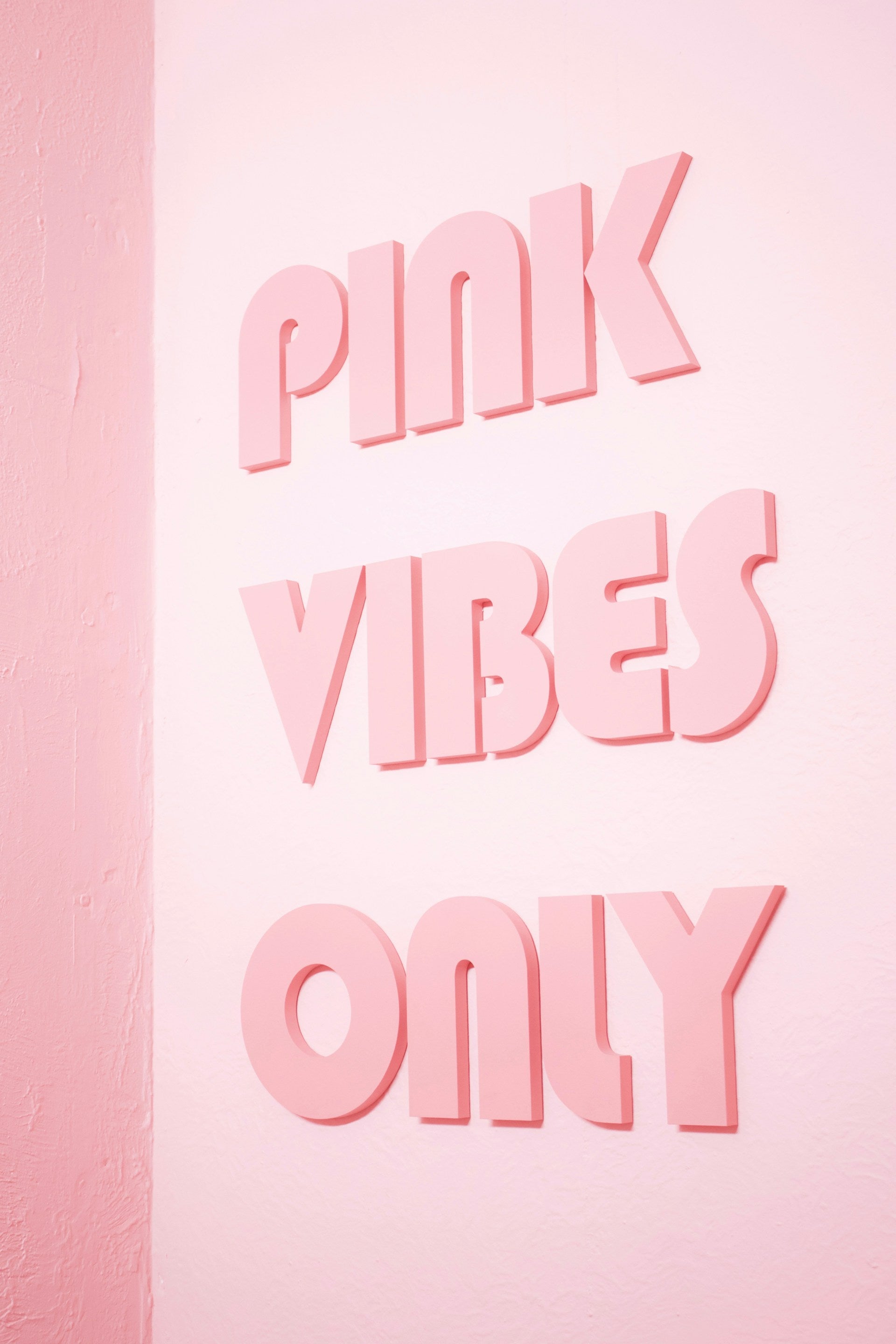 A pink sign on a light pink wall.