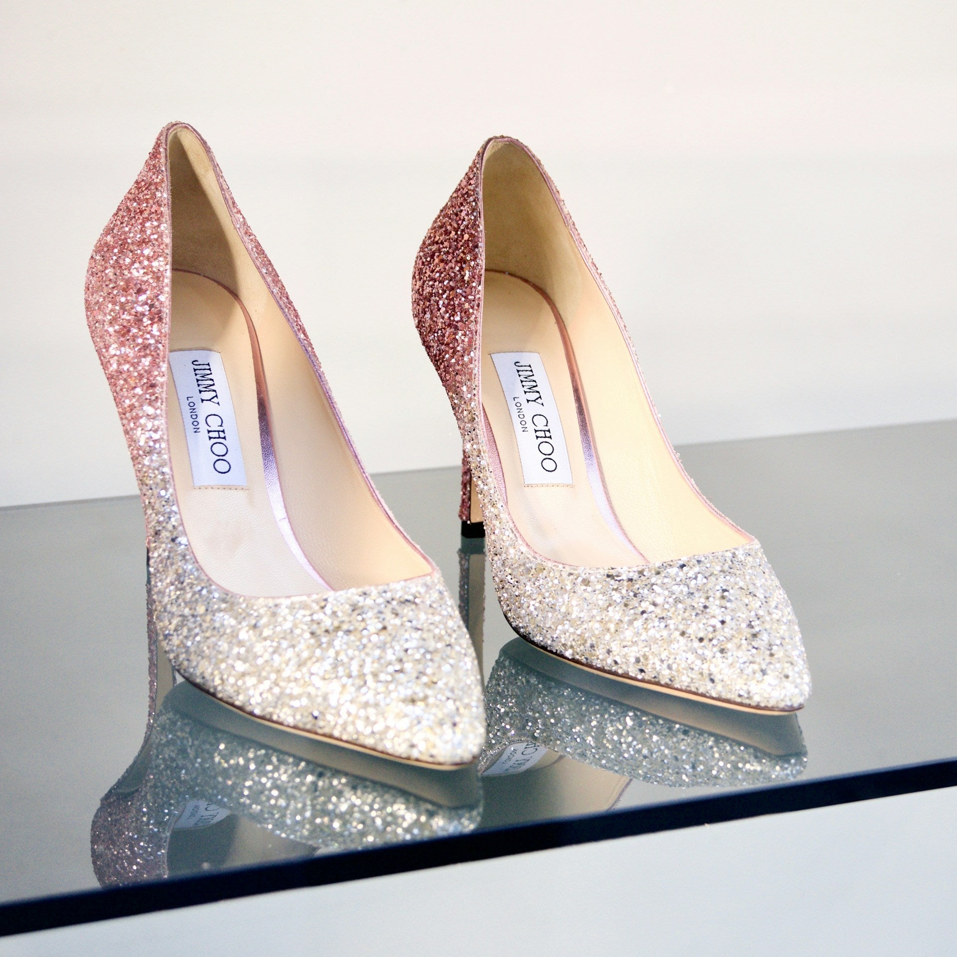 Sparkly high healed shoes on a glass shelf.