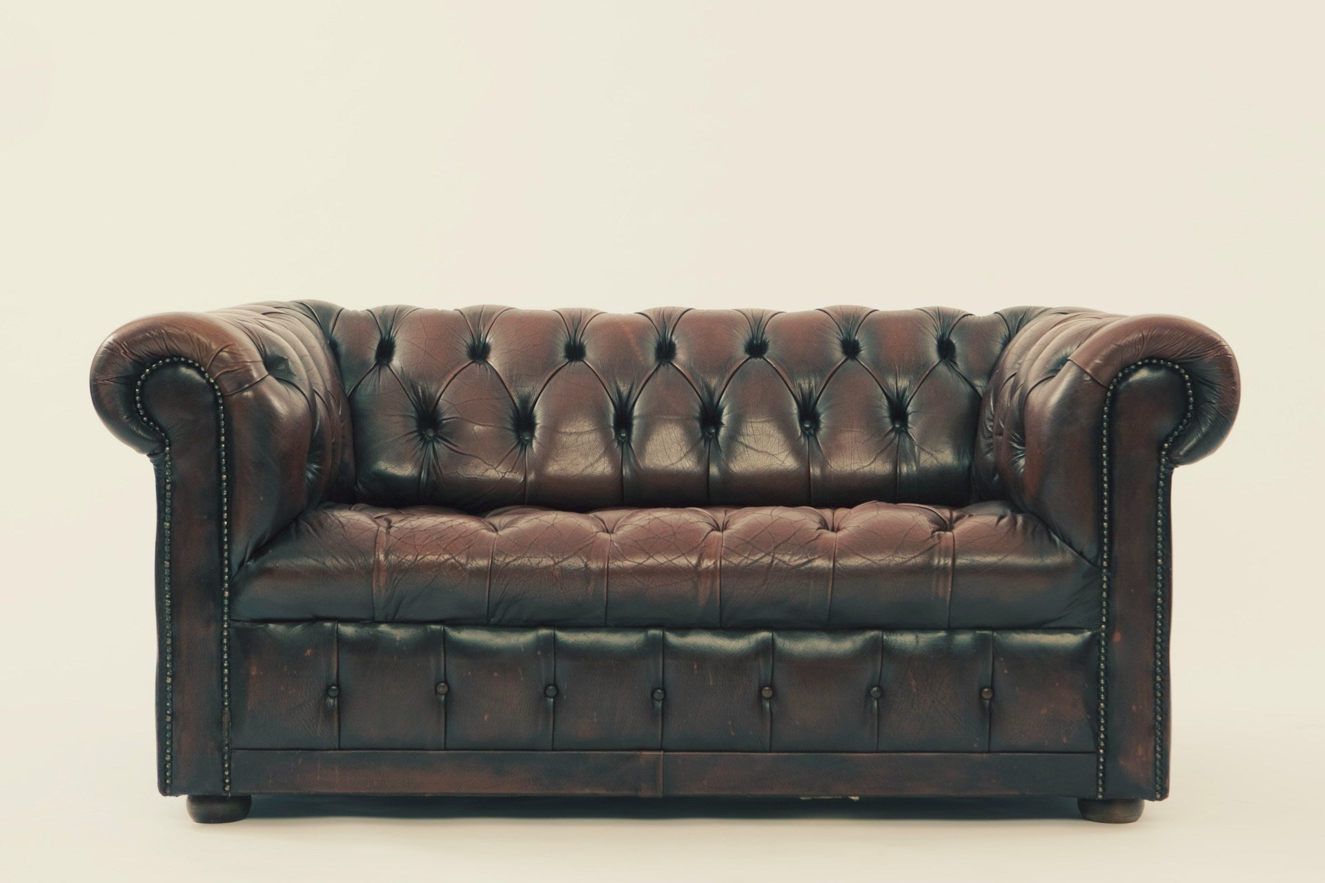 A brown leather sofa against a beige background.