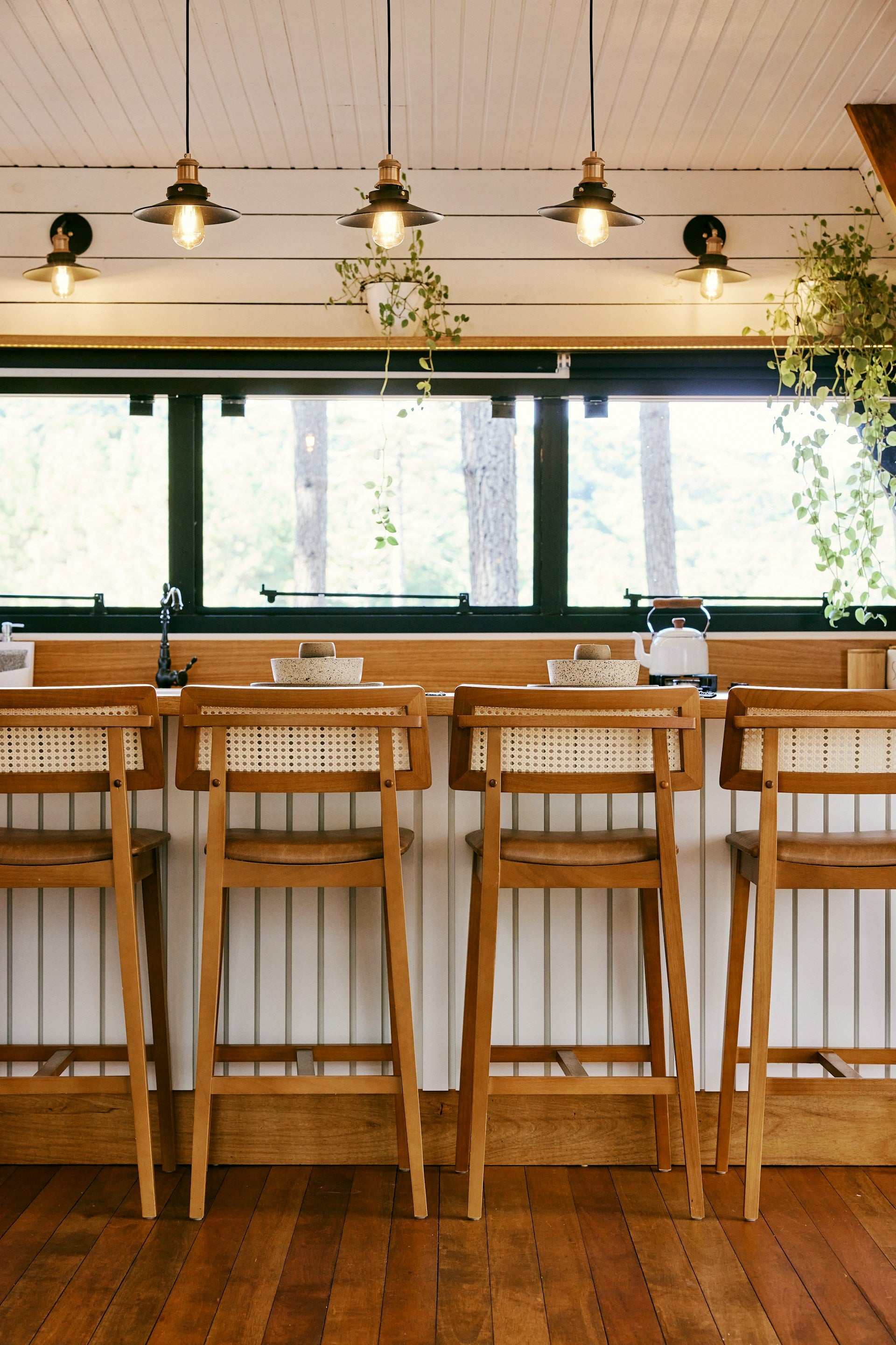 Wooden bar stools in the kitchen with dangling lights.