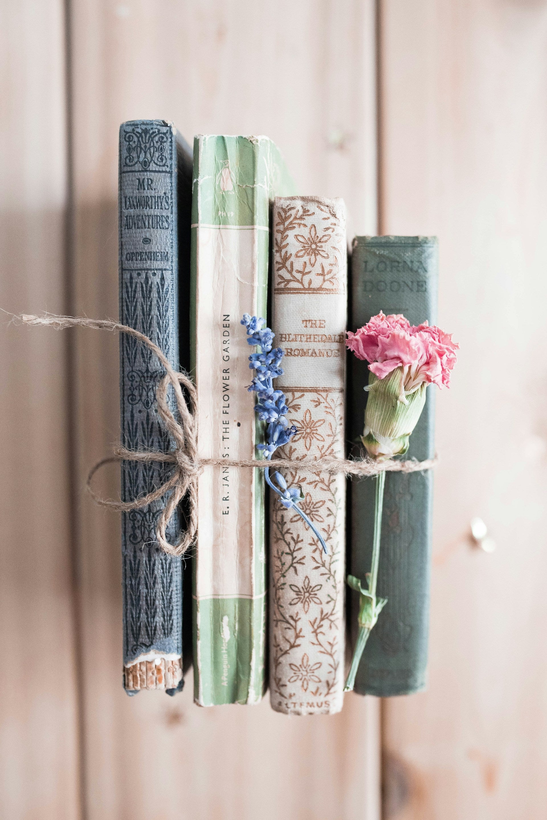 Four books held together by twine, with a flower.