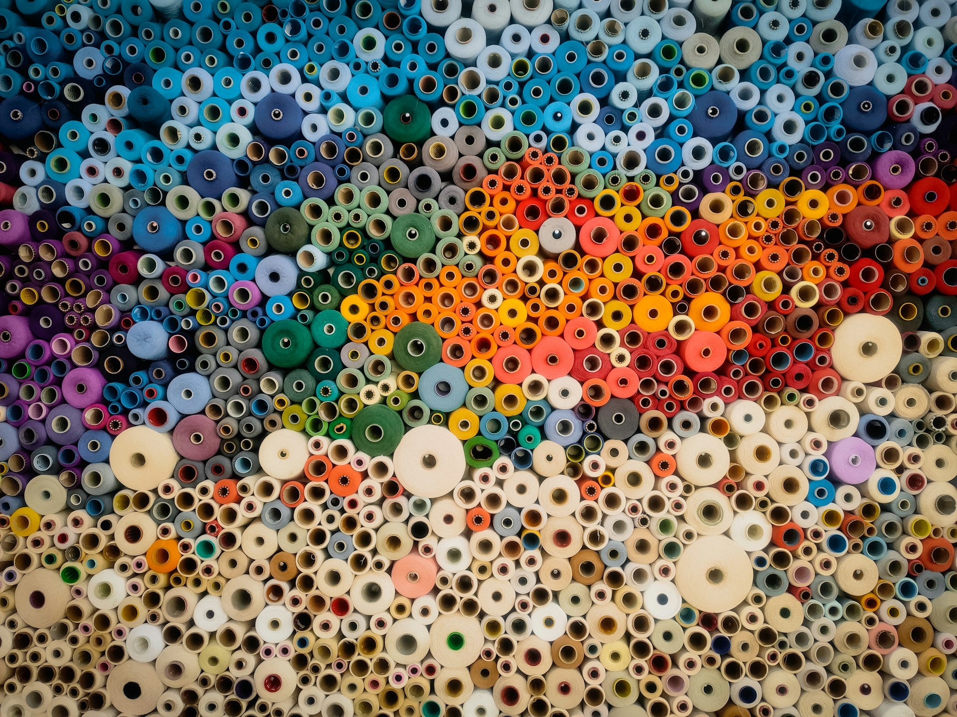 A stack of different colored spools of thread.