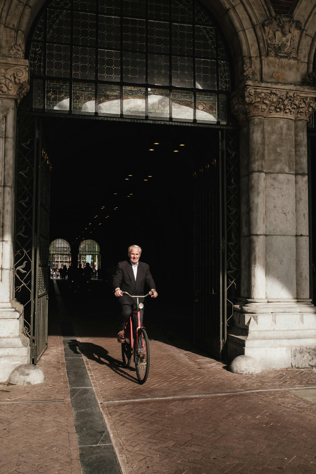 A person riding a red bicycle through a historical building.