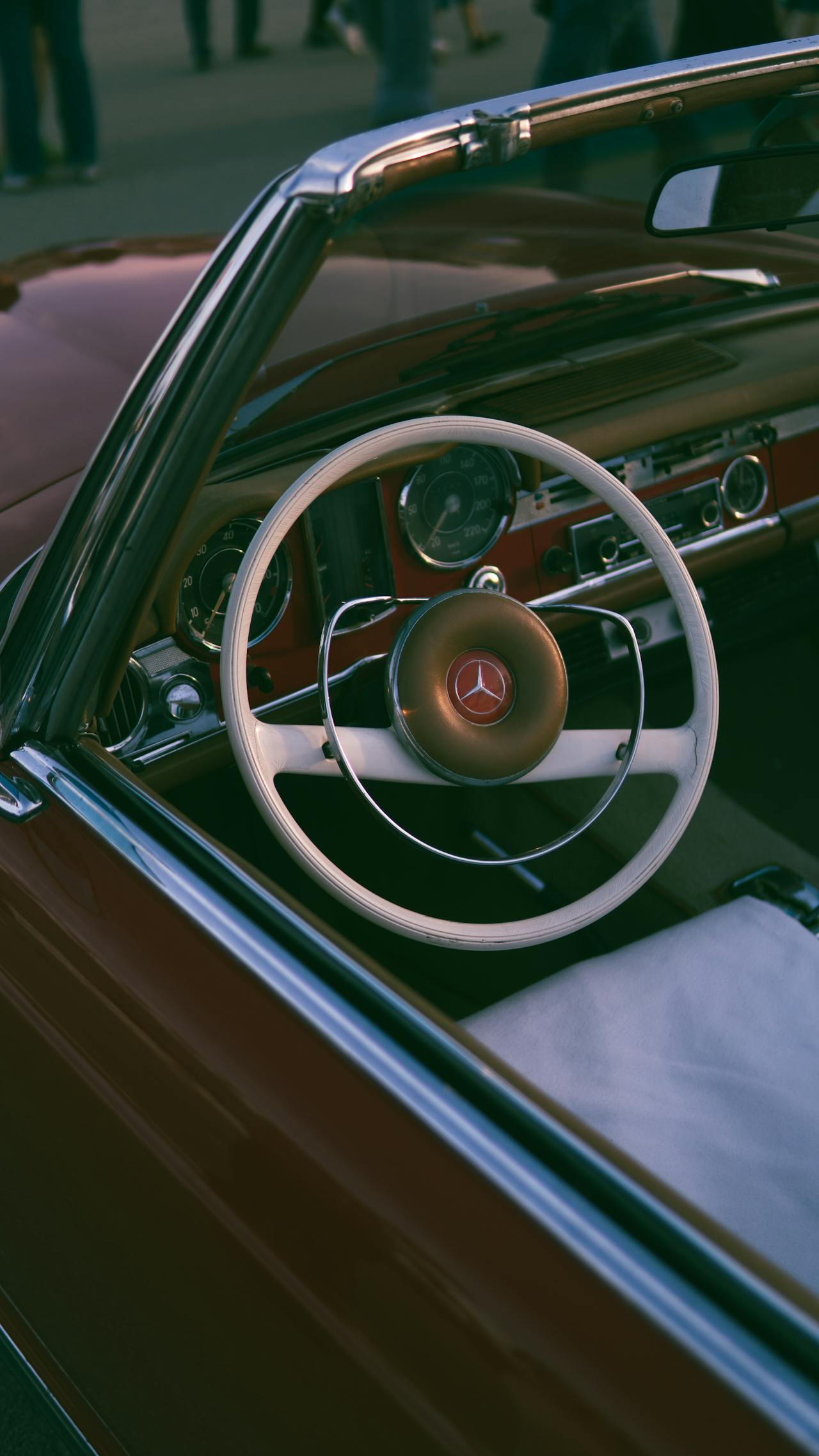A vintage red convertible with a white steering wheel.