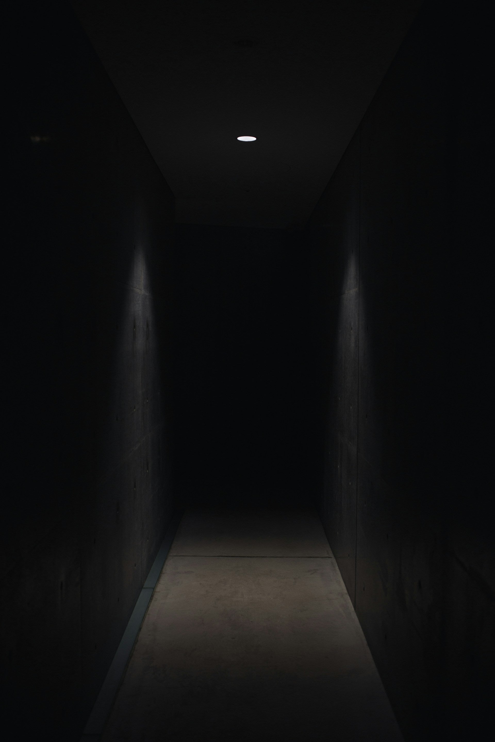 A dark hallway with a light shining in the middle.