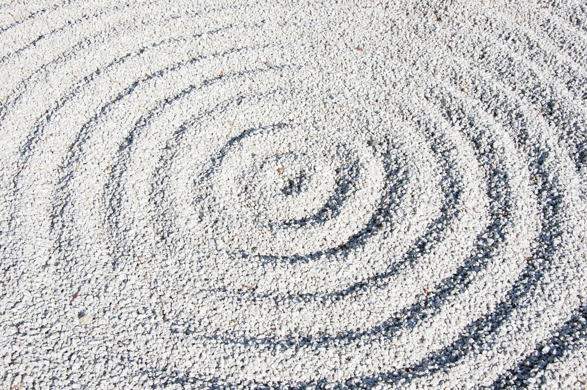An image of small rocks in a spiral pattern on the ground.