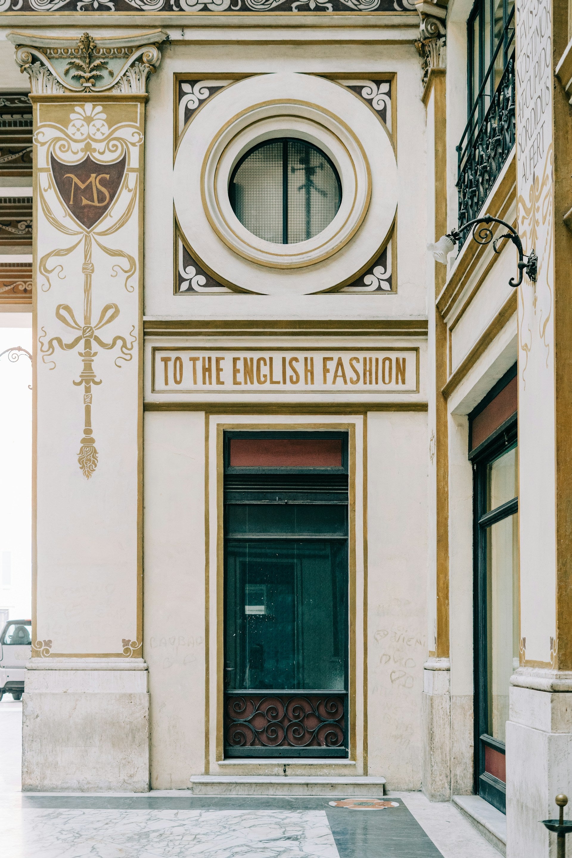 An old building in Italy with a sign and a circular window.