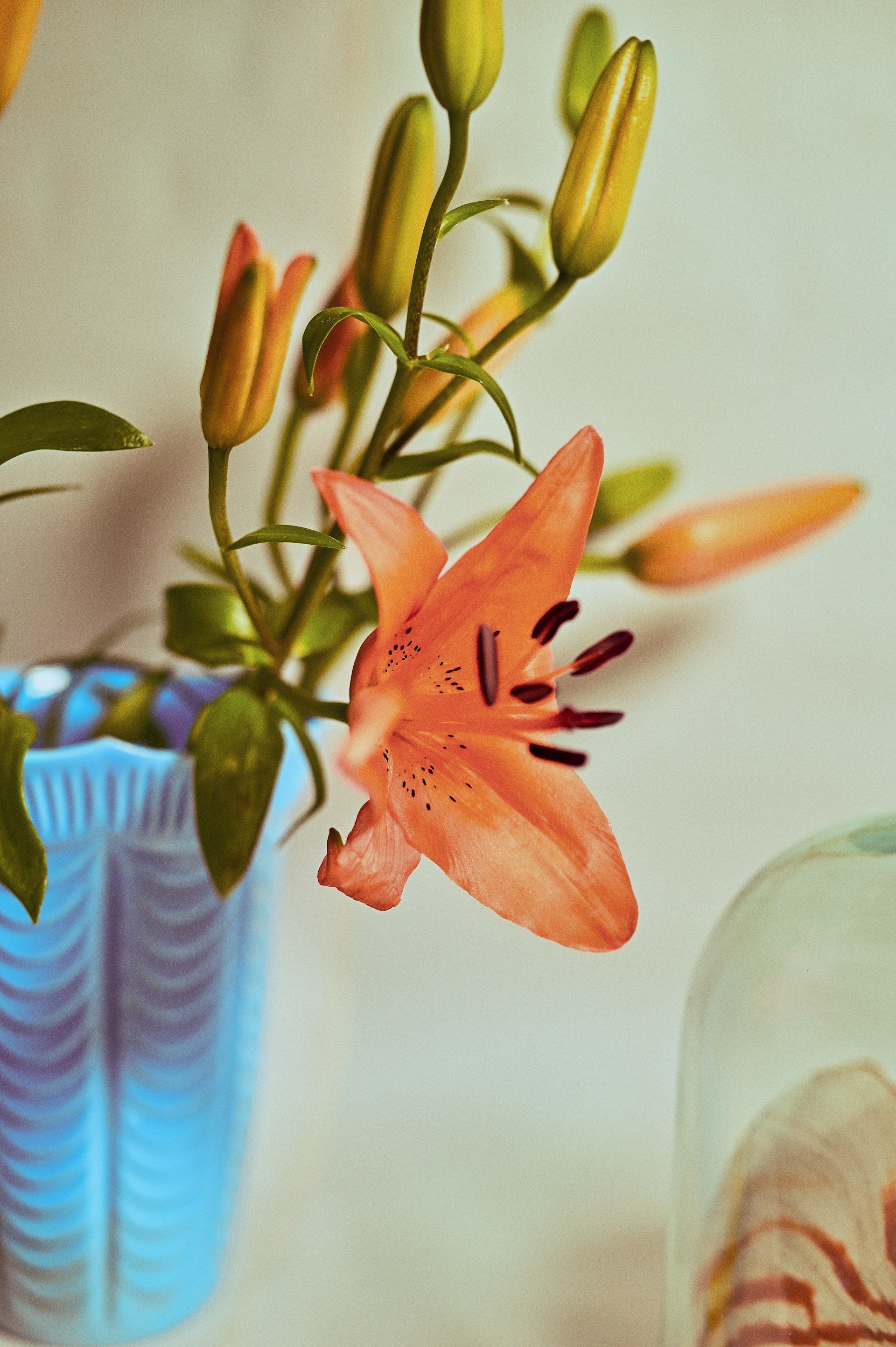 A blue vase on a table with orange flowers in it.