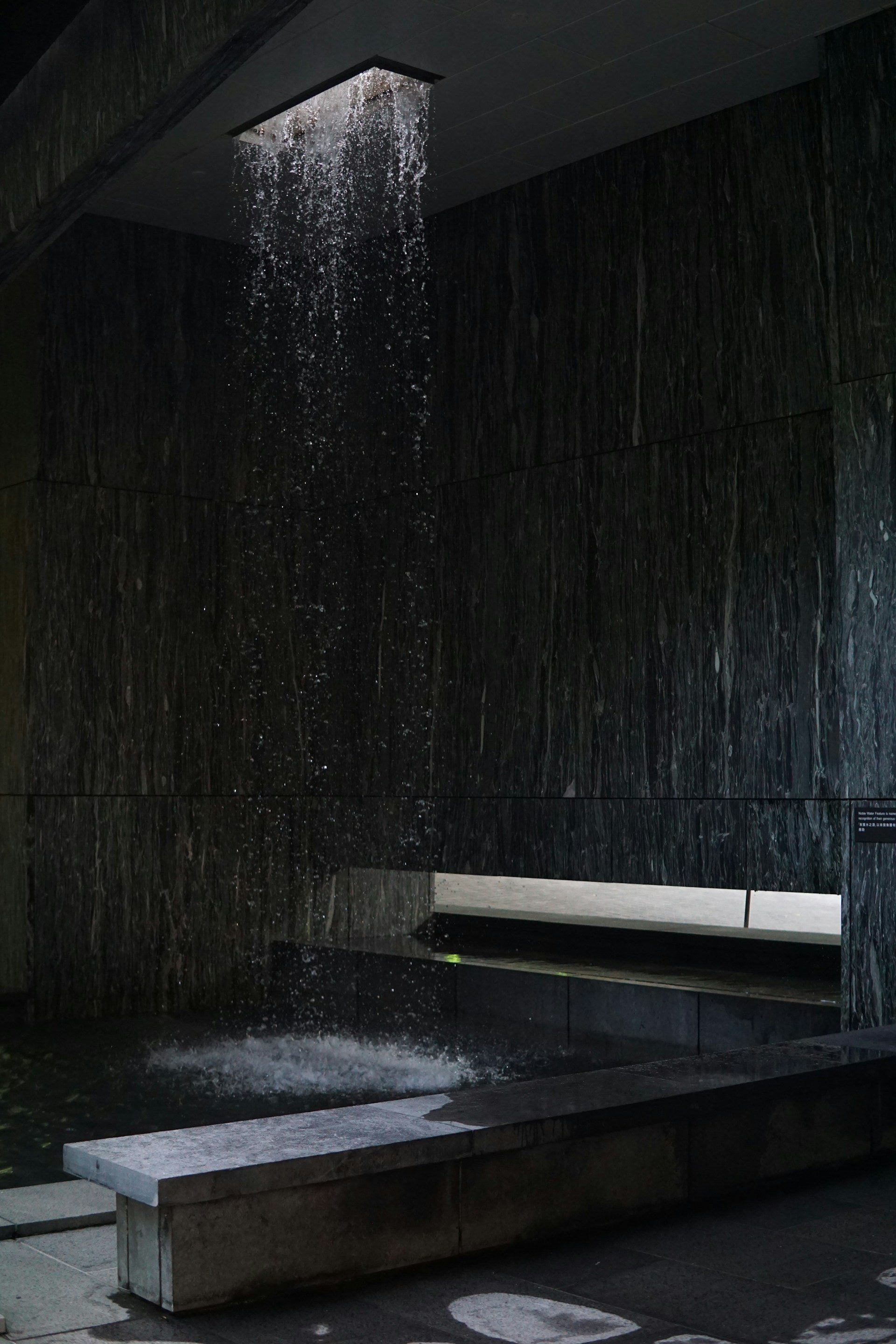A dark bathroom with a waterfall in the middle of it.