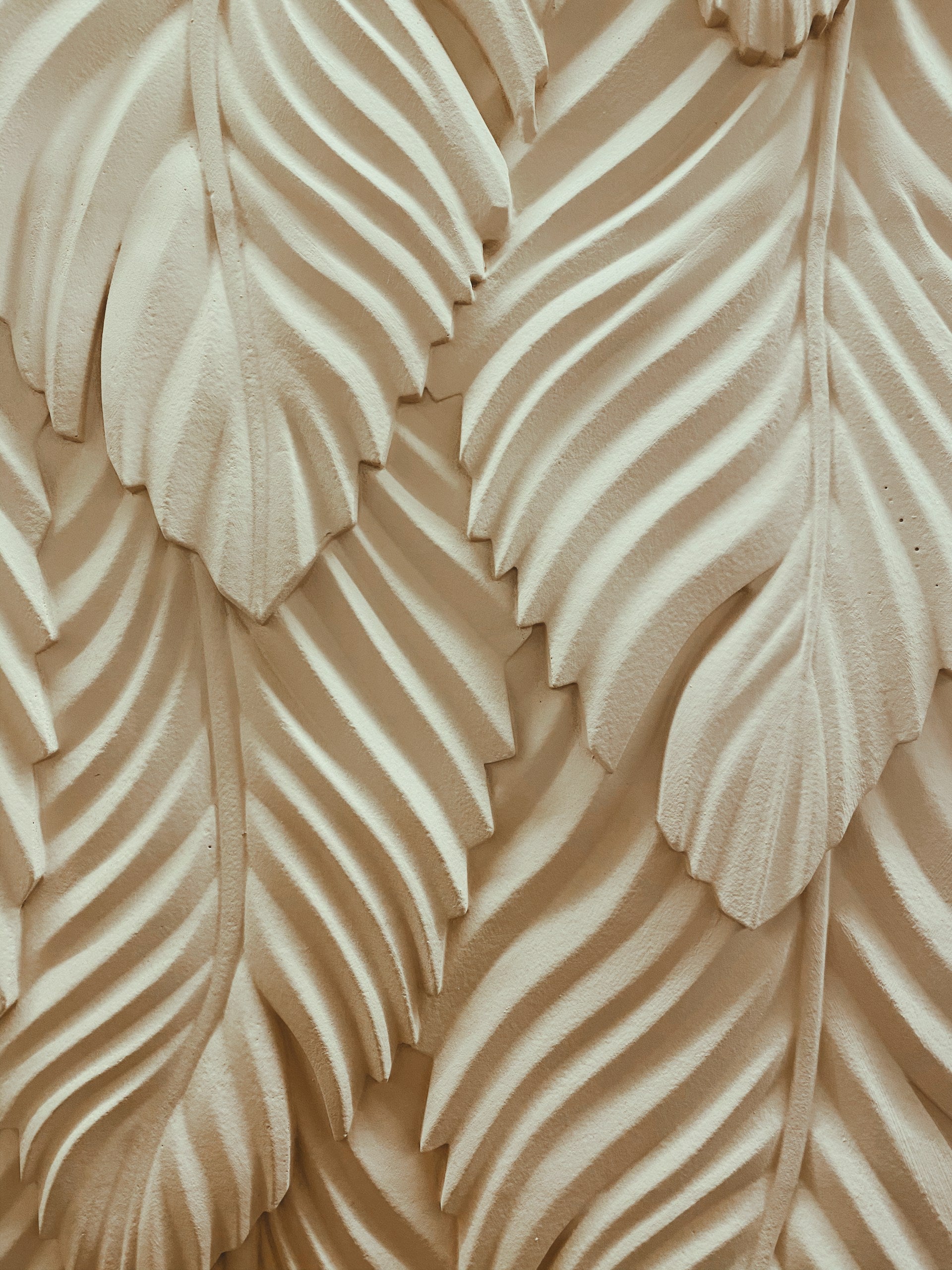 A close up of a cream decorative wall made out of leaves.