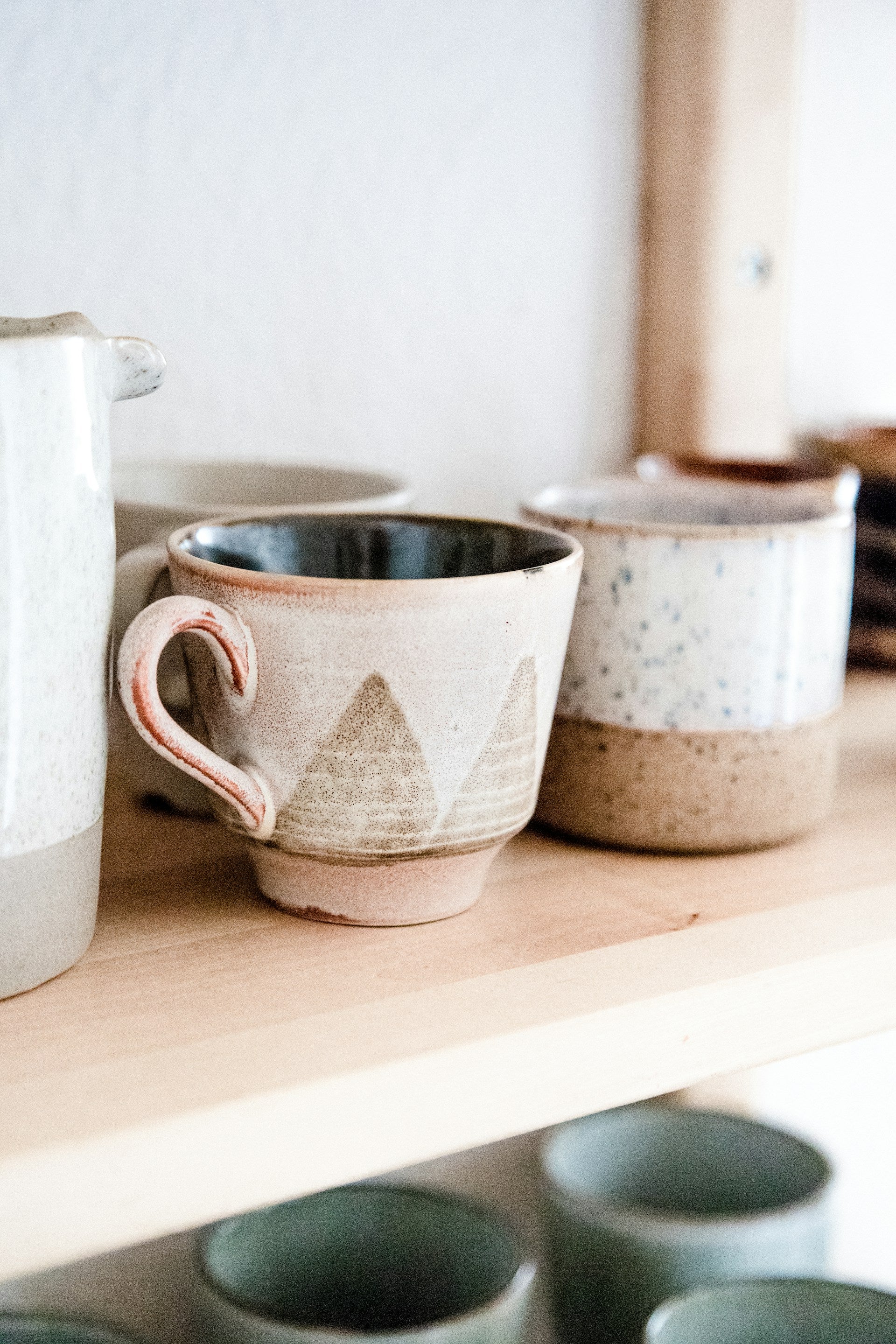 Rustic pottery cups on a wooden shelf.