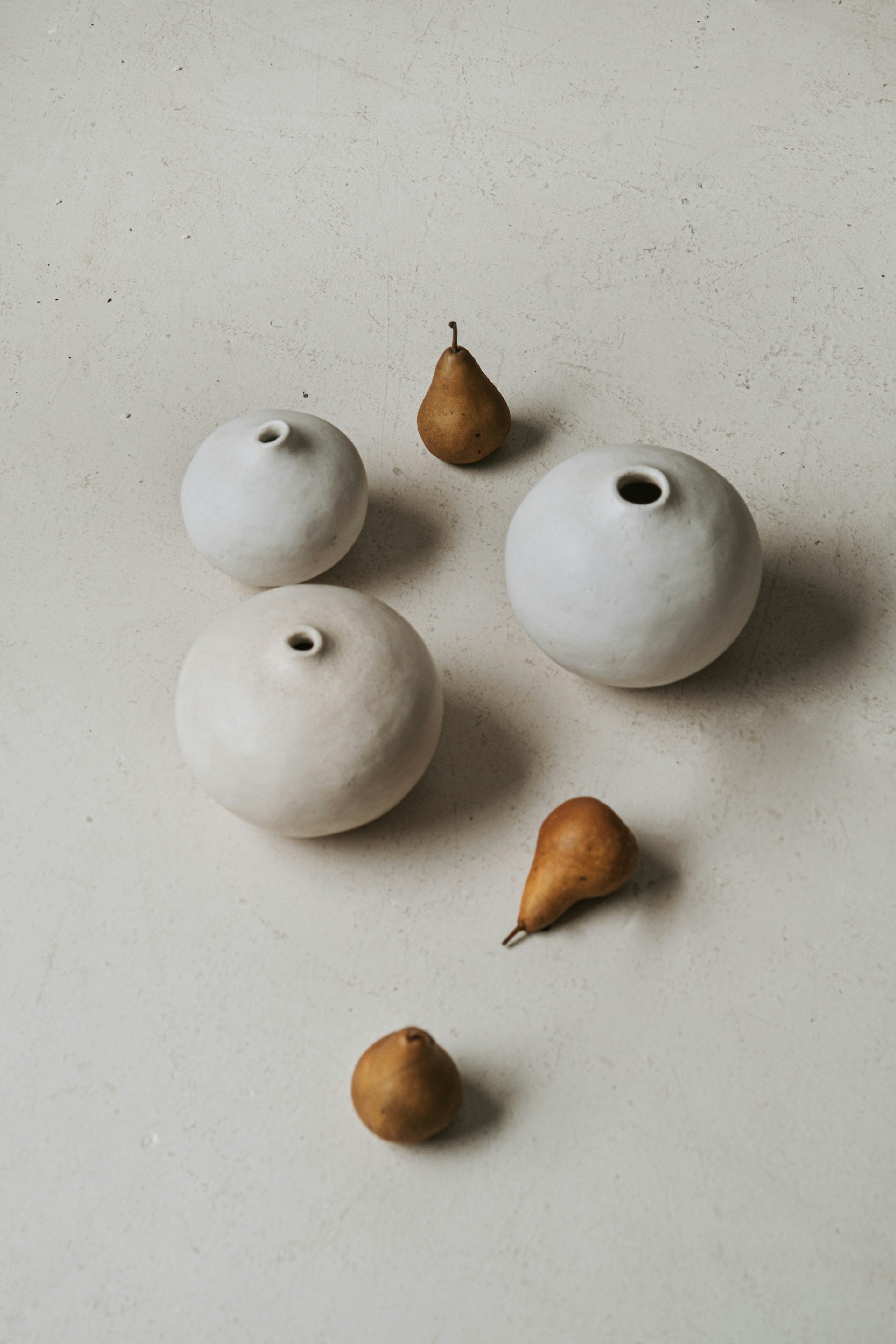 Three vases with pears placed around them.