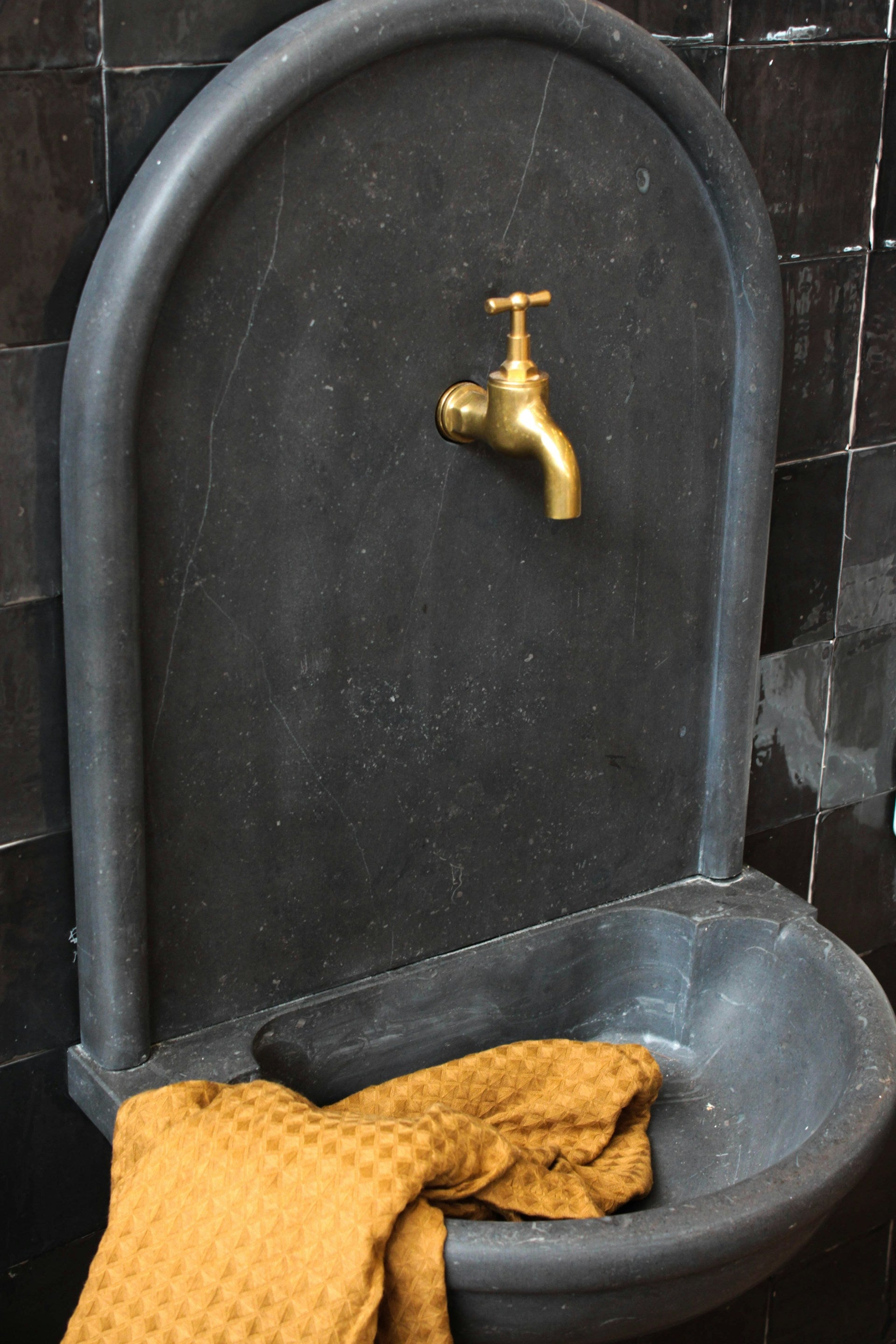 A black sink with an orange towel on it.