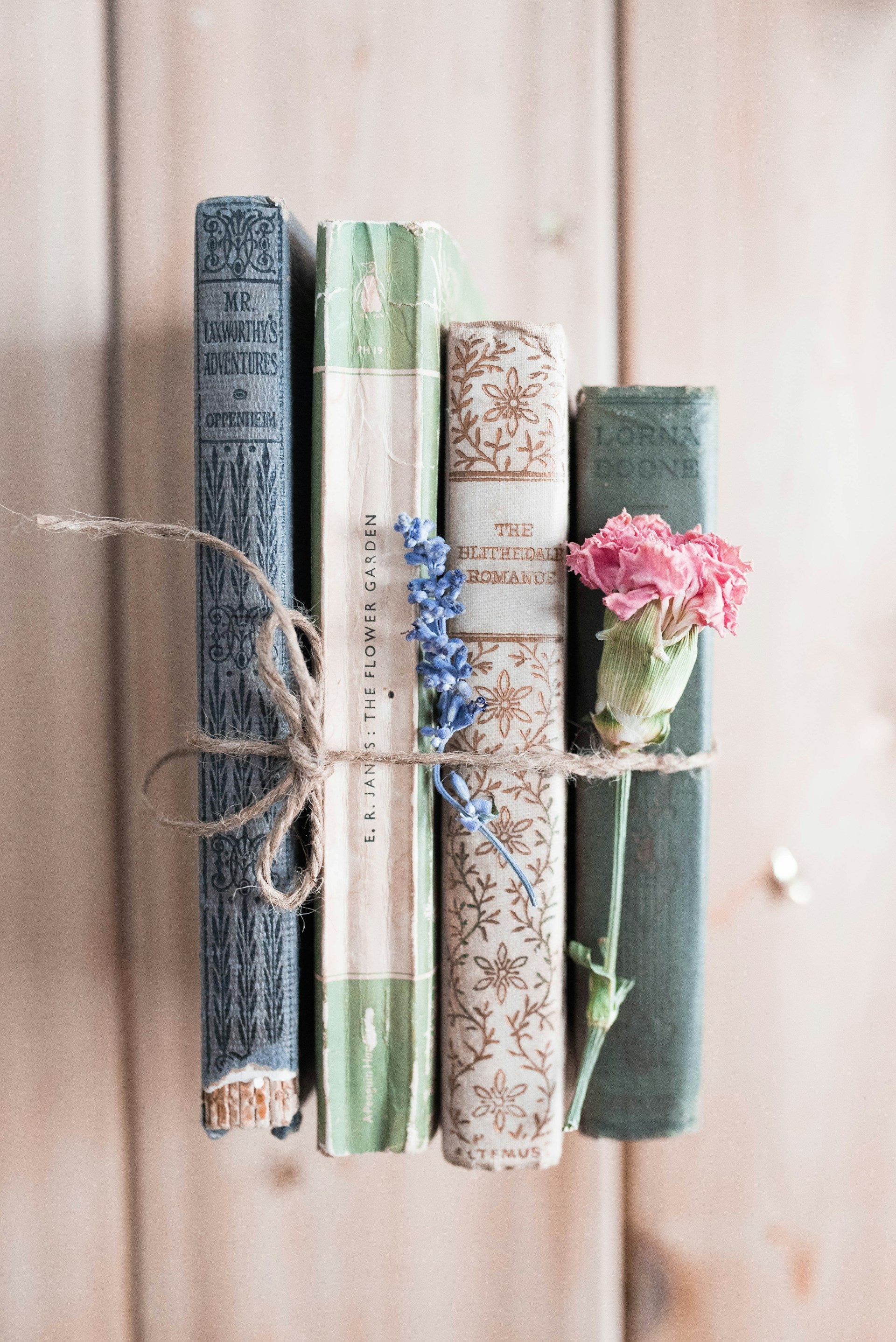 Four books held together by twine, with a flower.