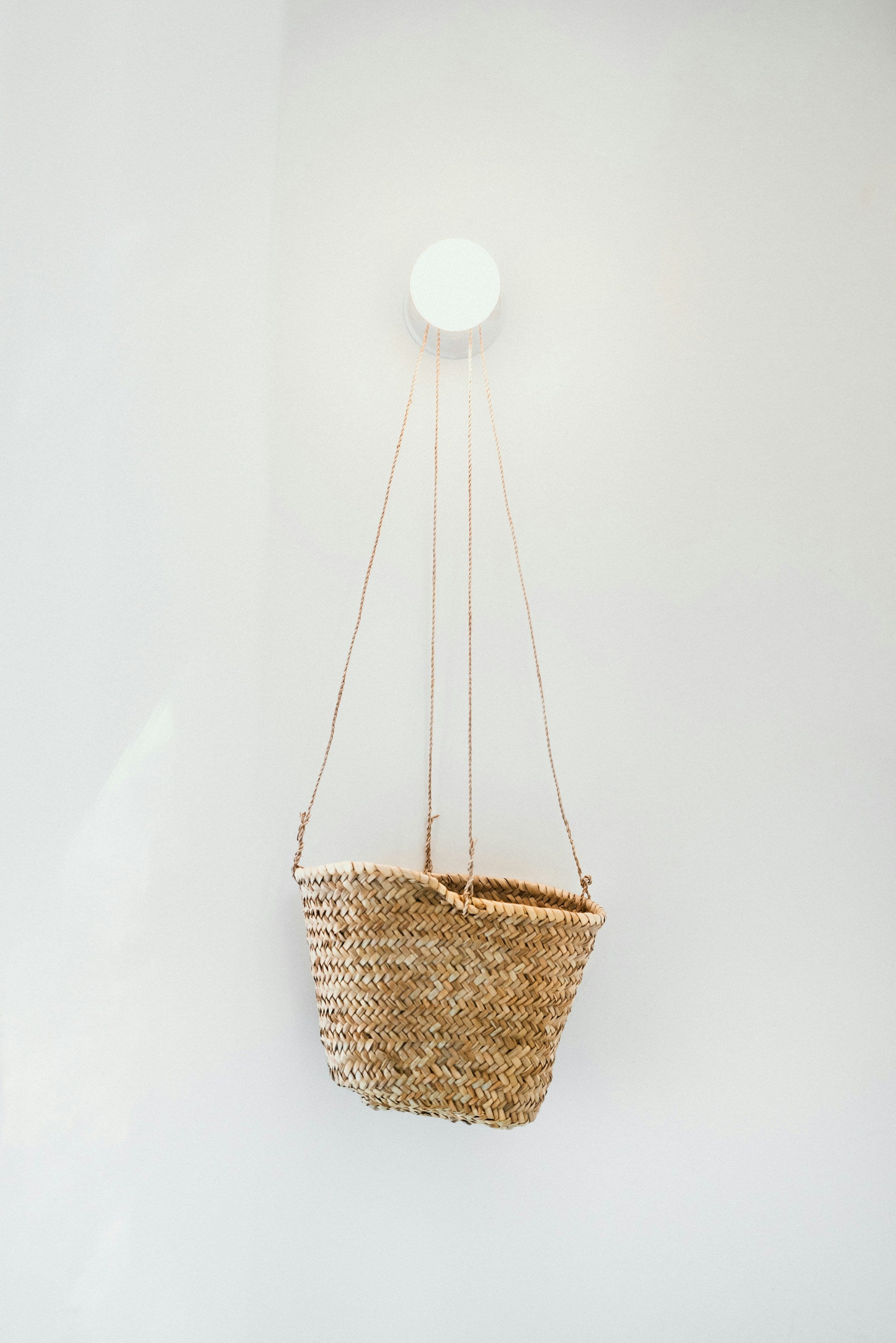 A whicker basket hanging on a white wall.